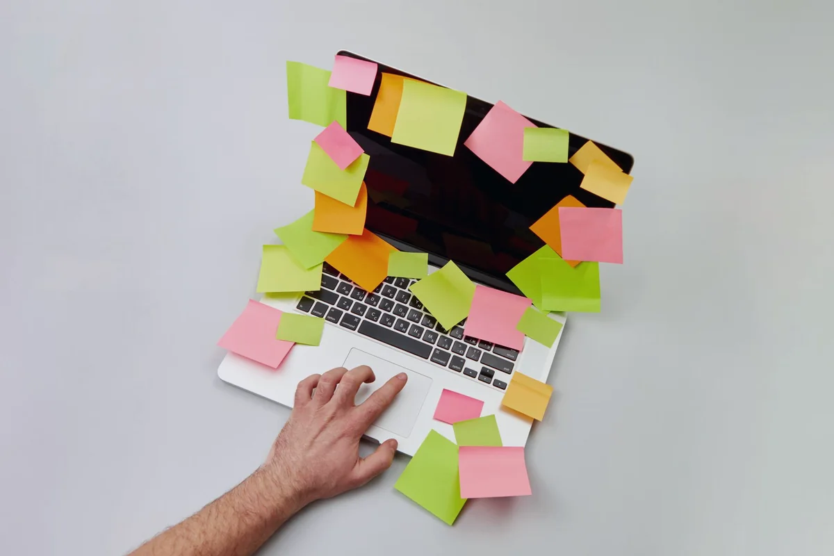 Laptop otoczony notatkami i zadaniami katalogowymi